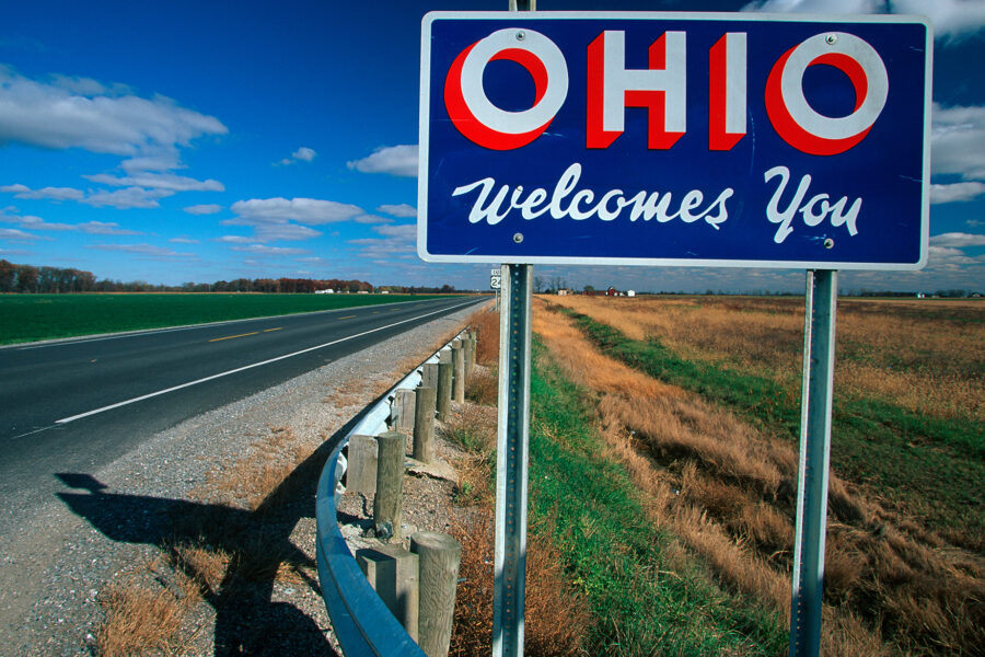 "Ohio welcomes you" sign on the highway, amongst grass and blue sky