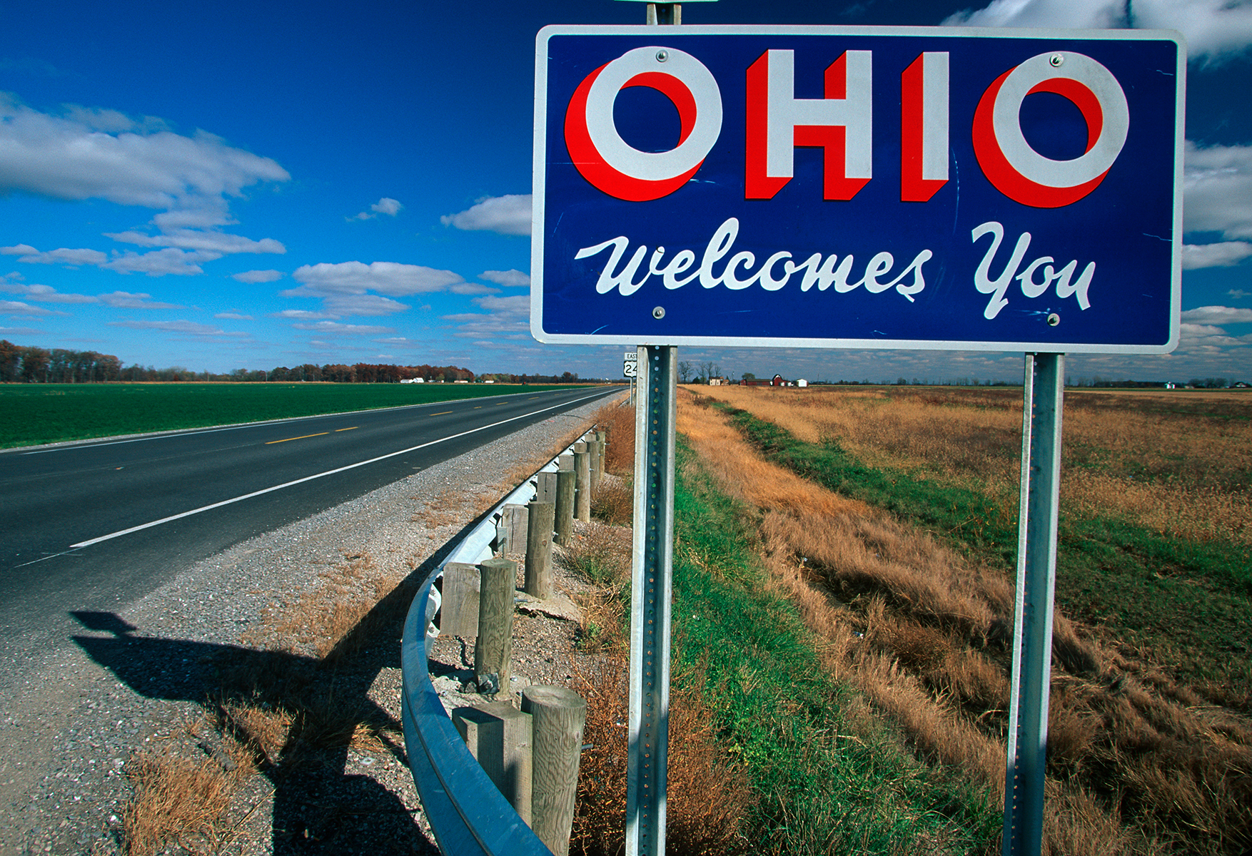 "Ohio welcomes you" sign on the highway, amongst grass and blue sky