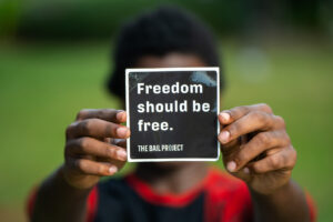 A client holding up a "Freedom should be free." sticker in front of their face.