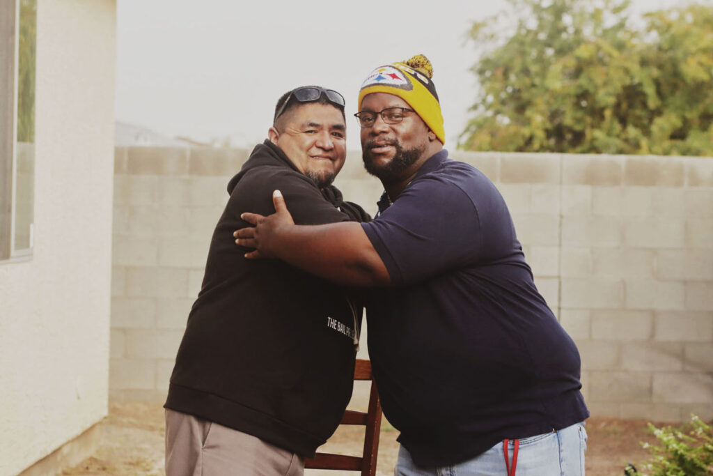 Phoenix client Albert shaking hands with another person outside by a brick wall