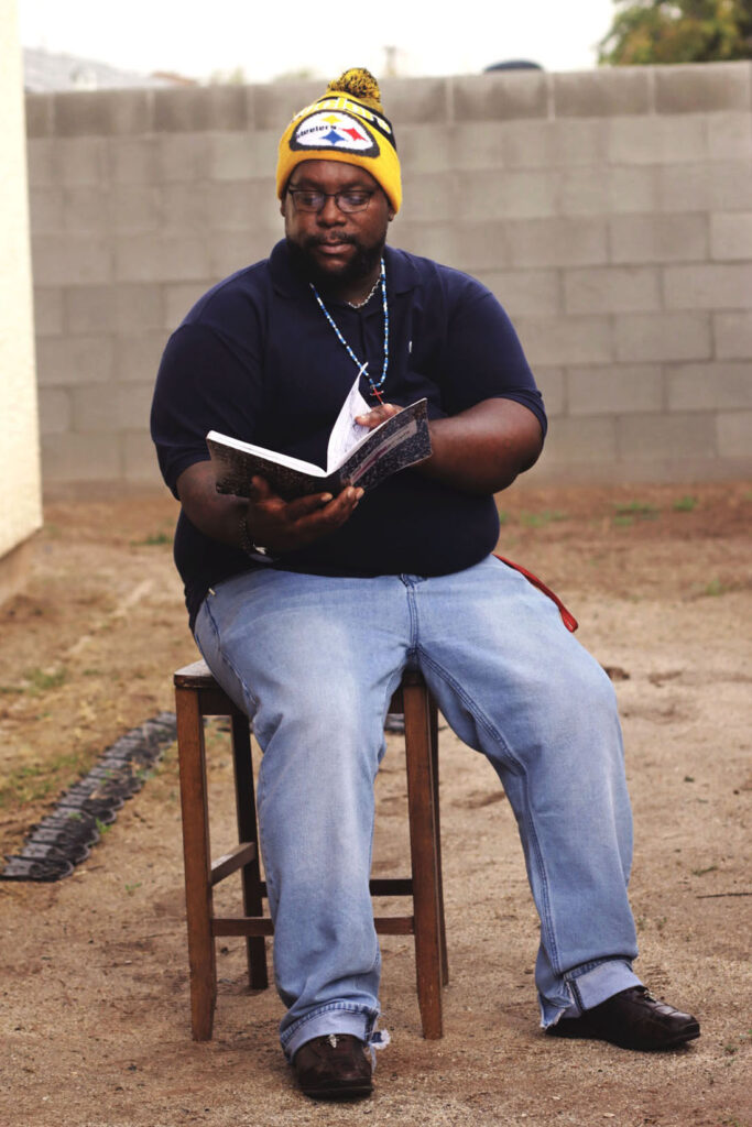 Phoenix client Albert reading a book outside by a brick wall