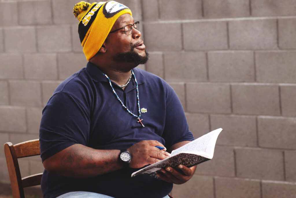 Phoenix client Albert reading a book outside by a brick wall