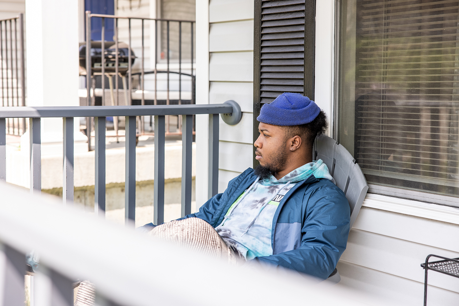St. Louis Client sitting on a porch chair in a jacket and hat