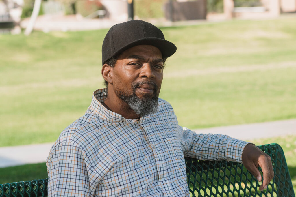 Phoenix client, Christopher, in a baseball cap sitting on a bench outside