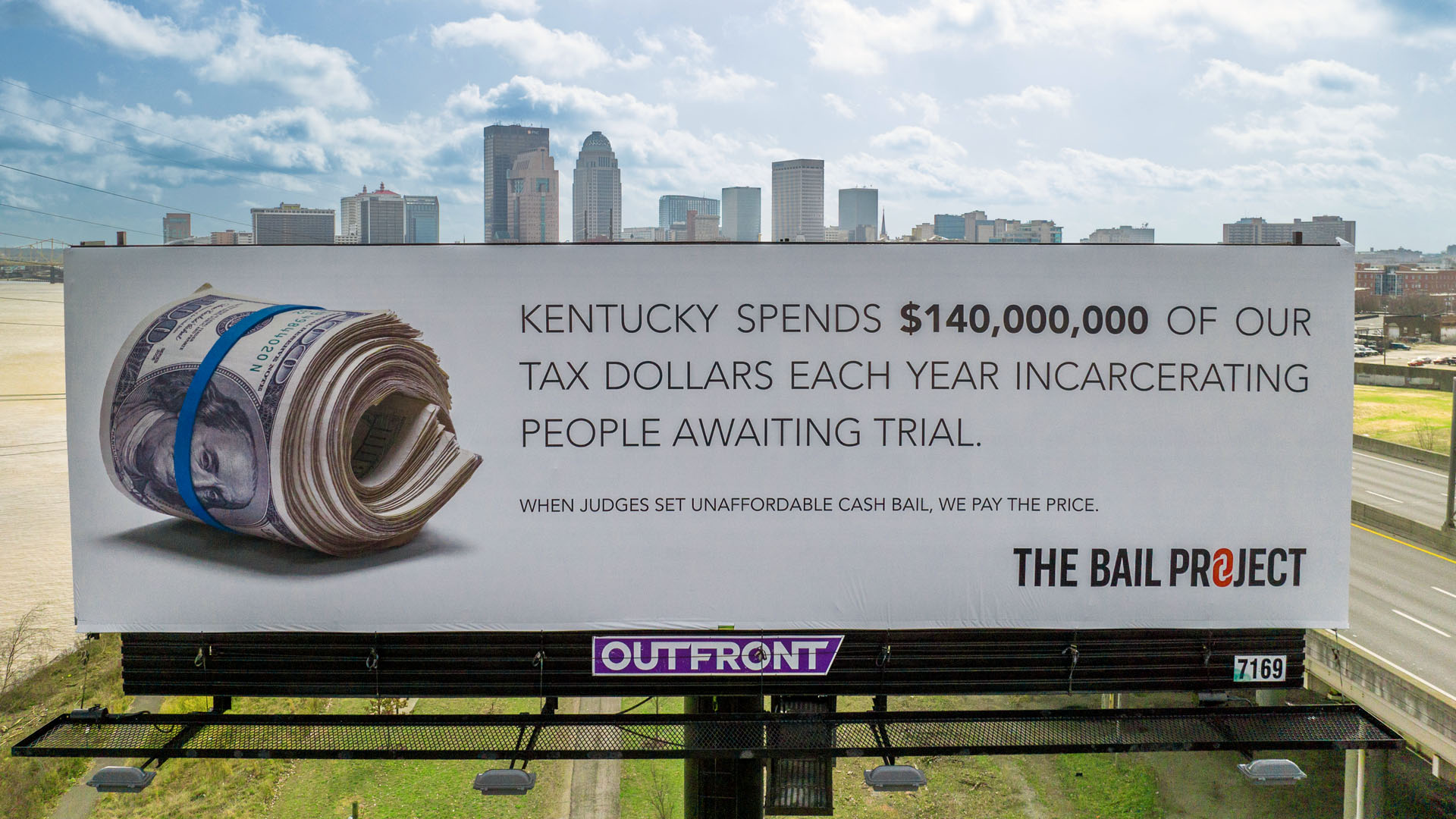 A Bail Project billboard in Kentucky featuring a roll of money, reading "Kentucky spends $140,000,000 of our tax dollars each year incarcerating people awaiting trial. When judges set unaffordable cash bail, we pay the price".