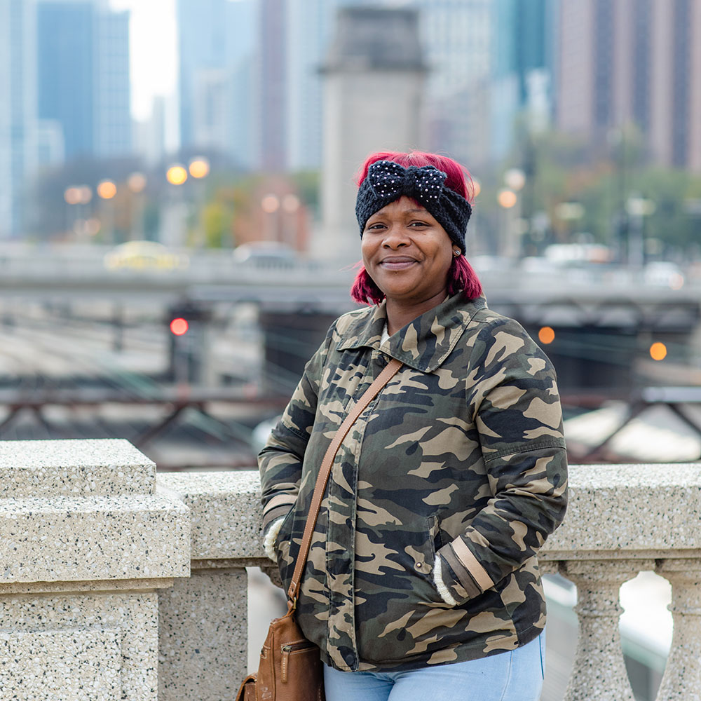 A woman on a bridge with a city in the background.