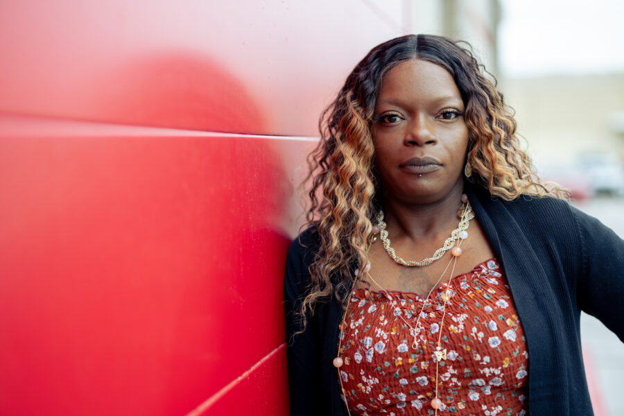a woman leaning against a red wall.
