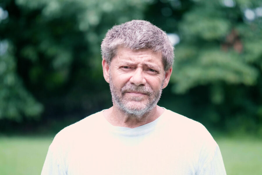 A man in a white shirt standing in a rural field.