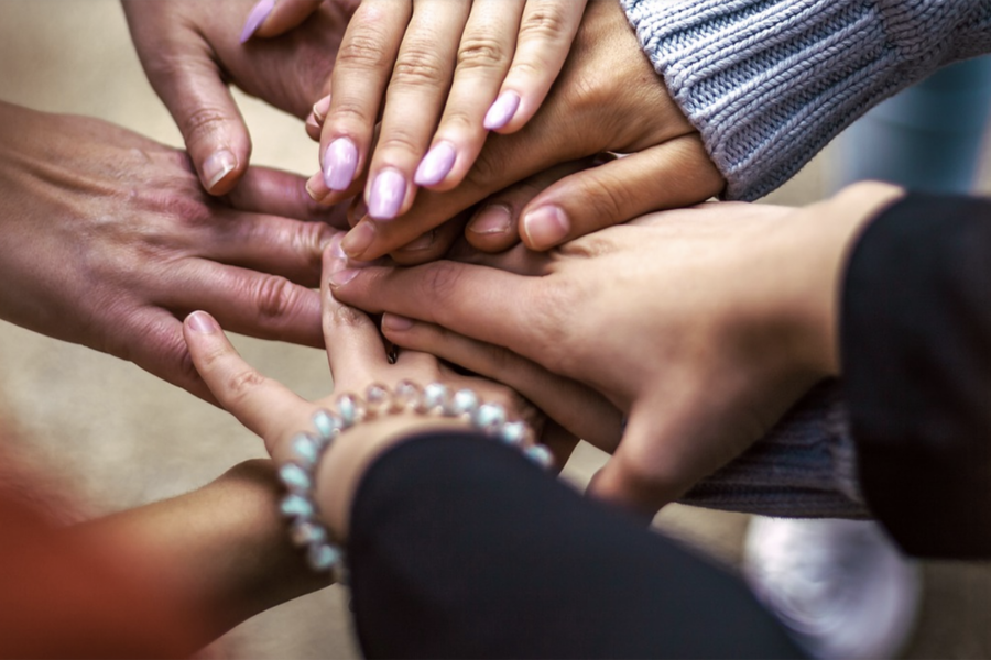 a group of people putting their hands together.