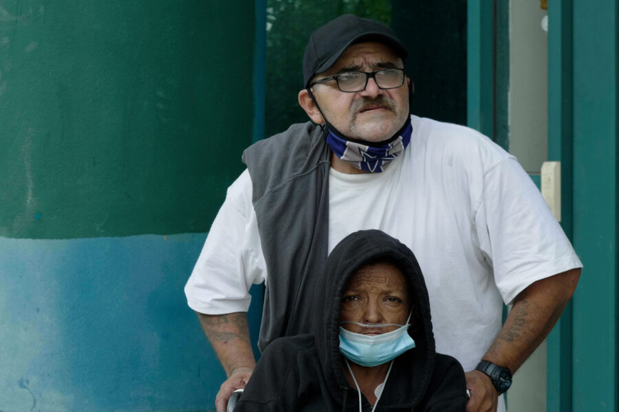 A man and a woman wearing face masks in Los Angeles, one in a wheelchair