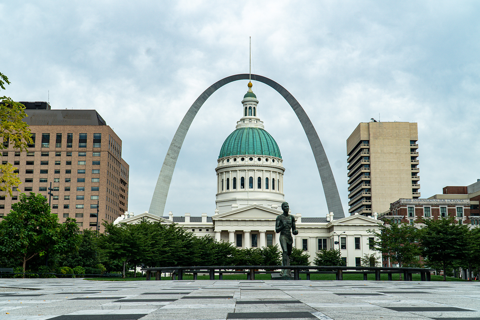 a capitol building stands in front of the St Louis arch.