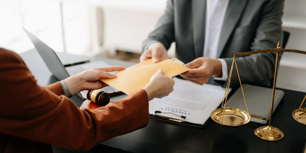Someone handing a yellow envelope of money over A desk