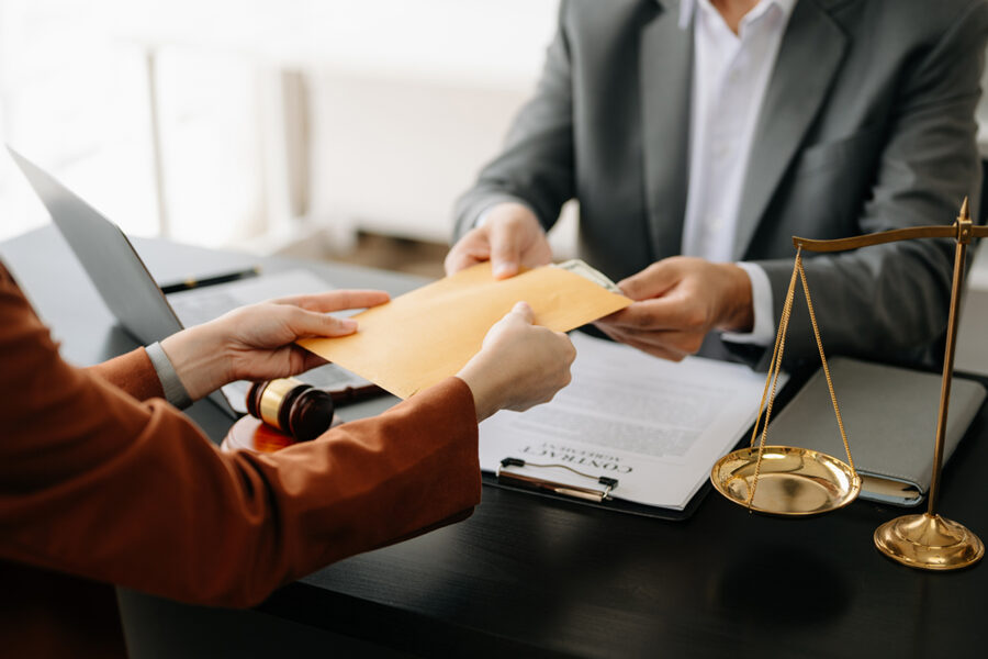 Someone handing a yellow envelope of money over A desk