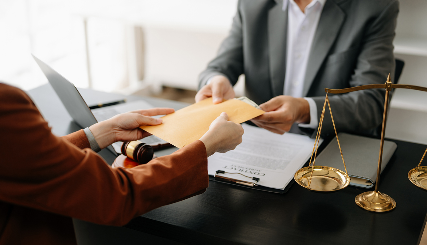 Someone handing a yellow envelope of money over A desk