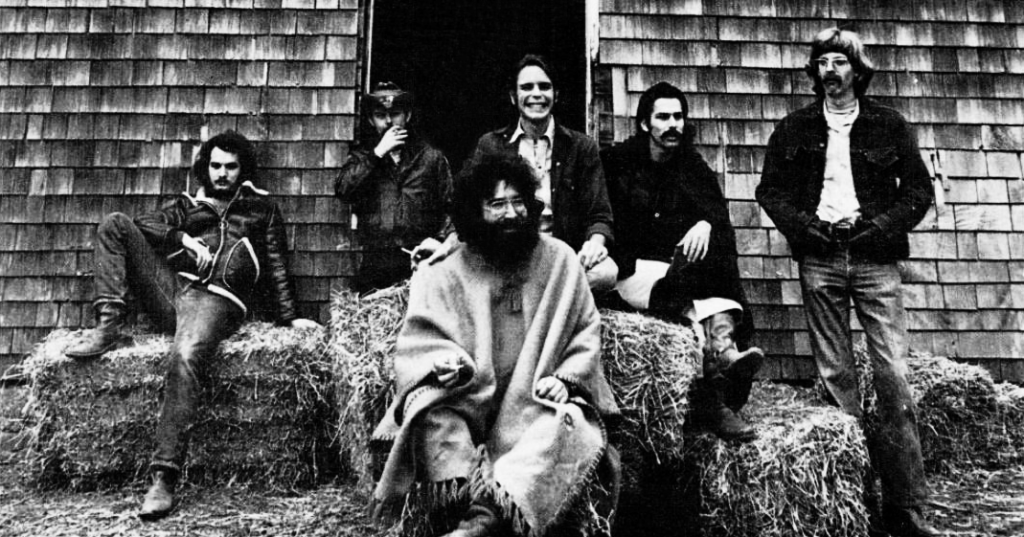 A black-and-white photo of members of The Grateful Dead standing outside by a building